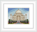 The image depicts a cross stitch pattern of the Taj Mahal framed in white, against a blue sky. The monument is represented with beige and white stitches, surrounded by greenery and small pink accents, suggesting a garden.