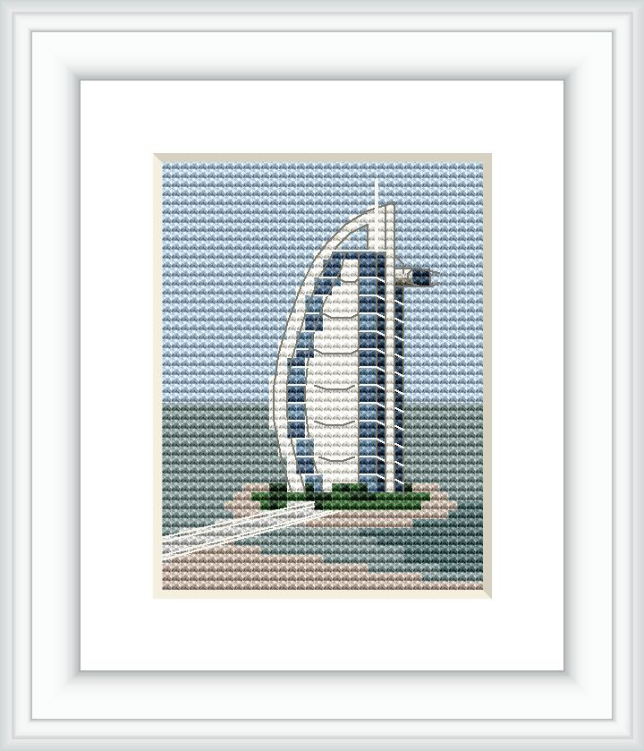 The image features a framed cross stitch pattern of a sail-shaped skyscraper set against a blue sky with fluffy clouds. The building is depicted with attention to its distinct curves and is surrounded by greenery and water, suggesting an island location.