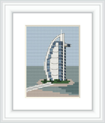 The image features a framed cross stitch pattern of a sail-shaped skyscraper set against a blue sky with fluffy clouds. The building is depicted with attention to its distinct curves and is surrounded by greenery and water, suggesting an island location.