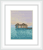 The image shows a framed cross stitch pattern of an overwater hut on stilts, set against a gradient sunset sky that transitions to a calm ocean's surface.