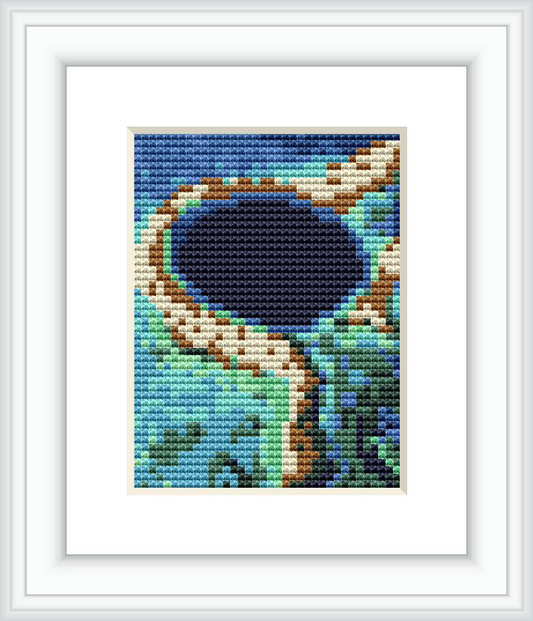 The cross-stitch pattern shows an aerial view of a lagoon with surrounding land and vegetation in various shades of blue, green, and brown.