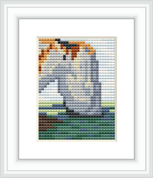 The picture shows a framed cross stitch pattern which appears to be inspired by Claude Monet's Impressionist painting style. It features an ocean scene with the natural stone arch of the Manneporte, in varying shades of blue, gray, green, ochre, and brown.