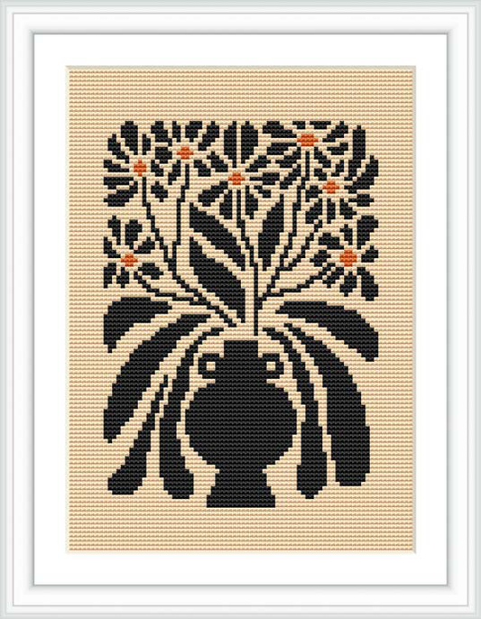 The image shows a framed cross-stitch pattern depicting a bouquet of flowers in a vase, predominantly in black with cream background and orange-tinted accents.