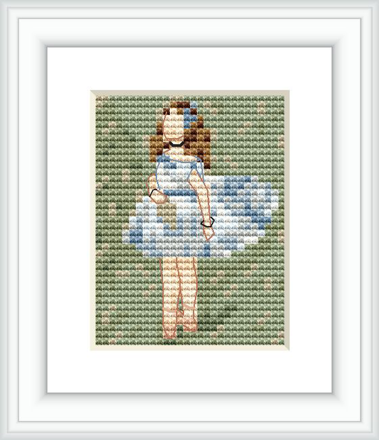 A cross stitch pattern depicting a young dancer in a blue dress standing, framed with a greenish background.