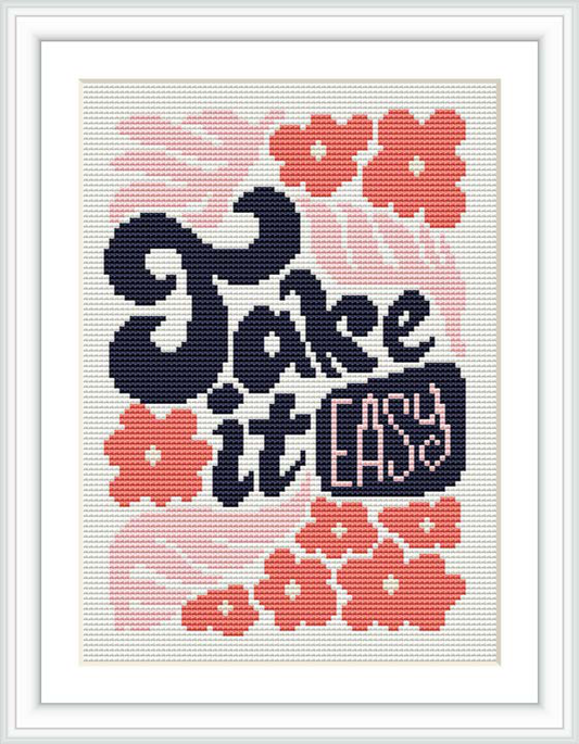 The image displays a framed cross stitch design which includes a stylized phrase 'Fake it till you make it', adorned with vibrant pink flowers and accents on a white background.