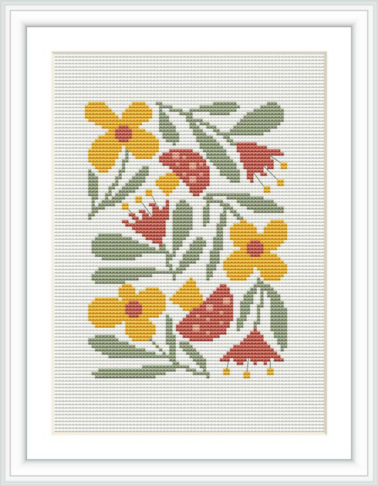 The image shows a cross stitch pattern framed and displayed on a wall. It consists of a variety of flowers with different shapes and colors, predominantly yellow and red, with green leaves, stitched on a white fabric background.