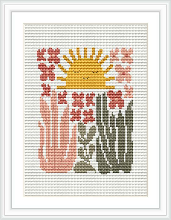 The image showcases a framed cross stitch pattern mounted within a white frame on a light background. The design depicts a stylized sun with a face at the top, surrounded by various blooming succulent plants in shades of green, pink, and grey.