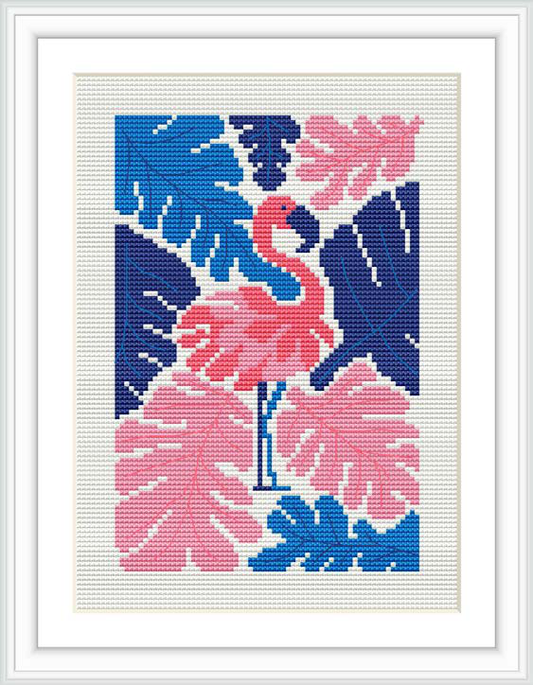 The image showcases a framed cross stitch embroidery featuring a stylized pink flamingo standing amidst tropical foliage. The background is divided into sections of dark and light blue, contrasting with the pink tones of the bird and the leaves.