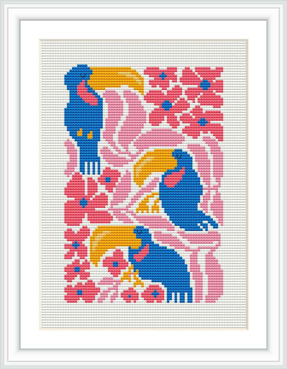 The image shows a framed cross stitch piece featuring a whimsical bird in stylized form with bold colors such as blue and pink, surrounded by floral motifs. The bird appears to be in a serene pose, with the design set against a white background.