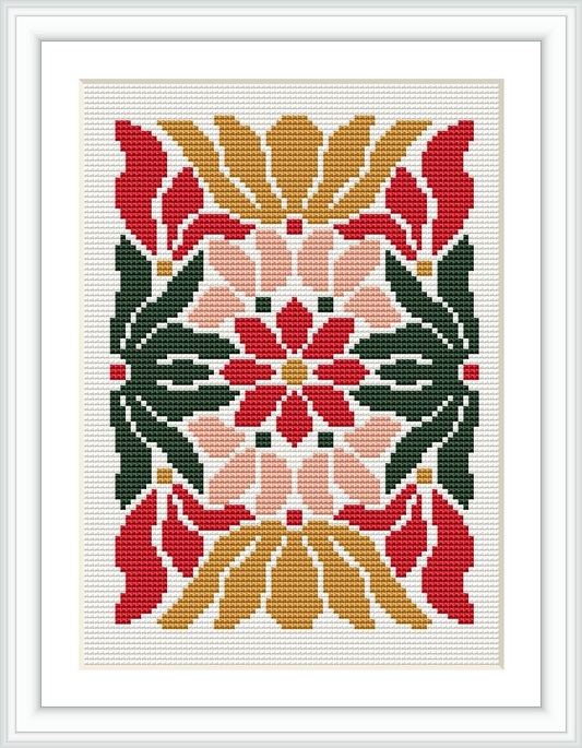 The image depicts a cross stitch pattern framed in white, featuring a symmetrical floral design with geometric elements. The flowers are stylized with a combination of red, green, gold, pale pink, and cream colors.