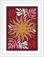 The cross stitch pattern showcases a central symmetrical floral design with petals in shades of red and pink, accented by white and gold. It is framed within a white mat and dark frame, set against a contrasting burgundy background.