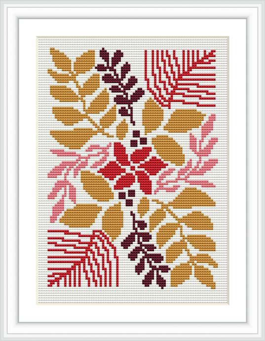 The image showcases a framed finished cross stitch design. The pattern displays a collection of stylized flowers and leaves, predominantly in shades of red, gold, and pink, artistically arranged against a white background.