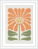 The image displays a framed cross stitch pattern of an orange flower with a central yellow core and green leaves, set against a white background.