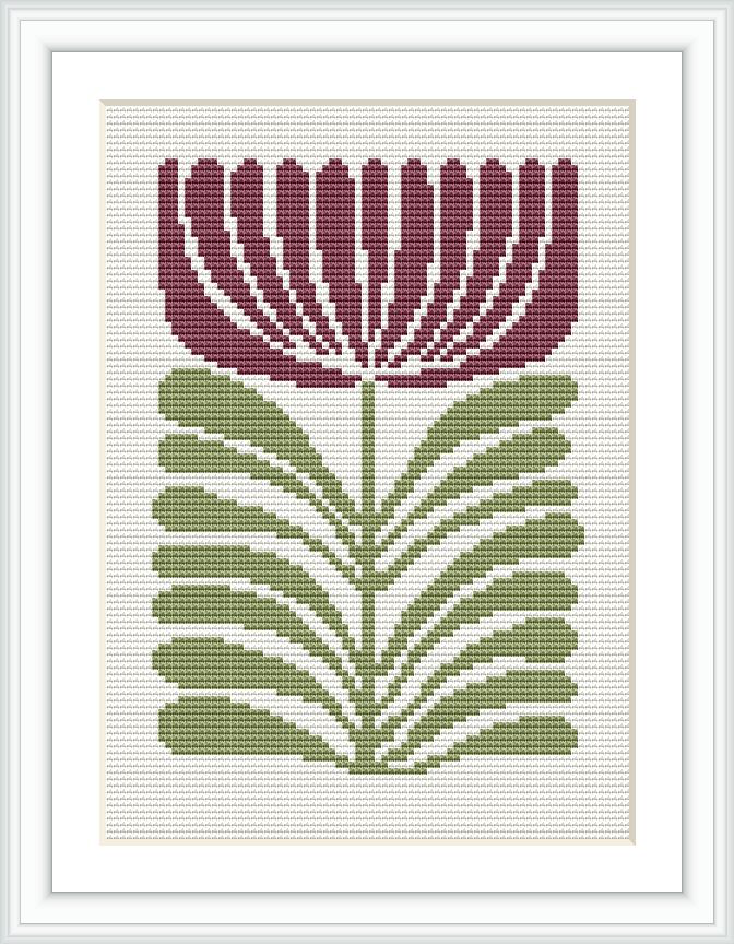 The image shows a framed cross stitch embroidery of a stylized flower with maroon petals and green leaves, centered on a white canvas.