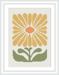 The image shows a framed cross stitch pattern featuring a stylized yellow flower with a central orange disc, surrounded by petals, sitting above two green leaves. The background is white.
