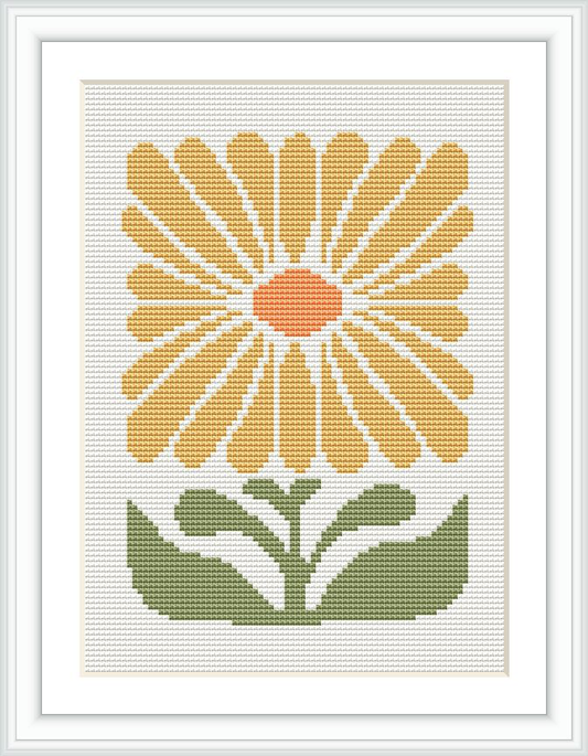 The image shows a framed cross stitch pattern featuring a stylized yellow flower with a central orange disc, surrounded by petals, sitting above two green leaves. The background is white.