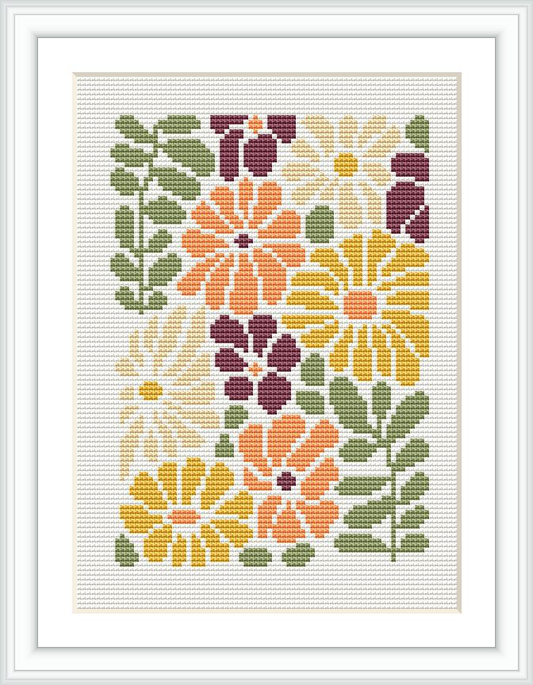 This image features a framed cross-stitch pattern with a design of colorful flowers in shades of mustard, peach, olive green, and burgundy. The floral design is arranged in a symmetrical pattern, filling the entirety of the white canvas.