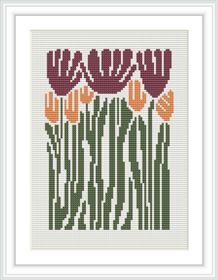 The image showcases a finished cross stitch pattern framed and hung on the wall. The design features a group of tulip flowers in various colors standing erect with lush green leaves and stems against a cream or white background.