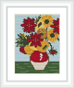 The image shows a cross stitch pattern of a floral arrangement with sunflowers and red poinsettias in a two-toned vase, all set against a light blue background with a simple green base resembling grass.