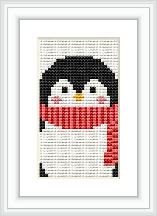 The image displays a framed cross stitch pattern of a penguin with a red and white striped scarf, centered on a white canvas and surrounded by a simple white frame.