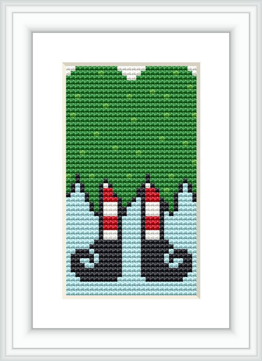 The image presents a cross-stitch pattern featuring the bottom half of two gnomes against a blue and green background, showcasing their iconic red conical hats and black boots.