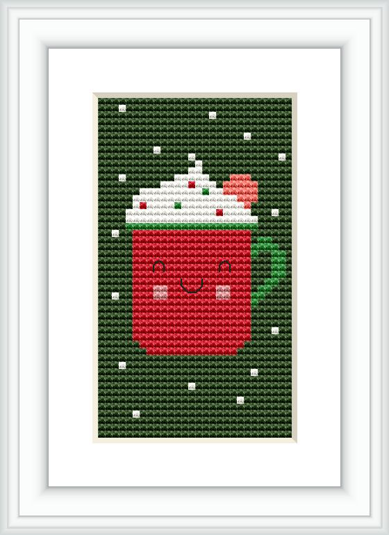 The image displays a cross stitch pattern of a red mug with a white lid and a green handle. The mug features a smiley face design, set against a green background with scattered white dots.