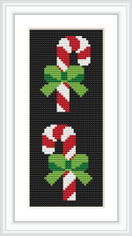 The image displays a vertically oriented cross-stitch pattern of two candy canes with green bows, set against a black background, framed in white.