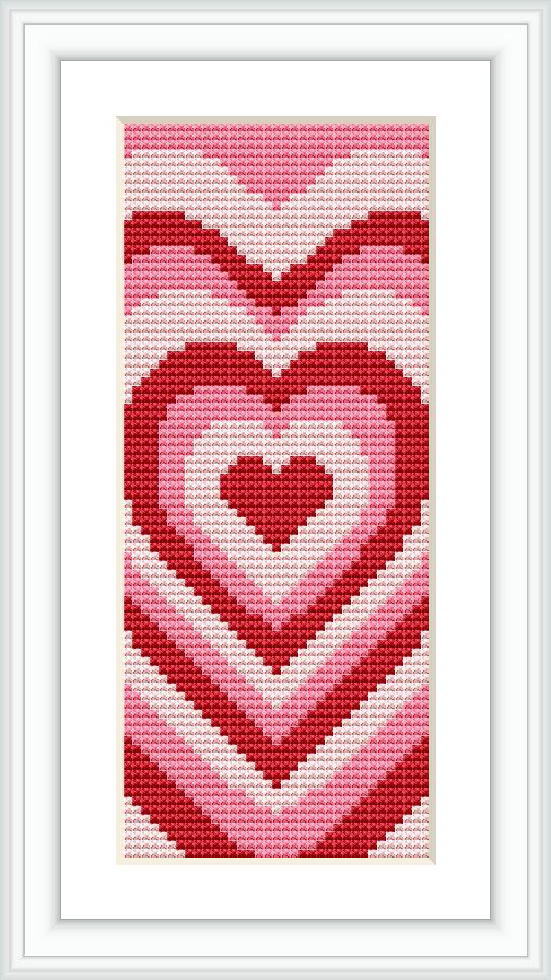 The image showcases a framed cross stitch piece of a heart-themed bookmark with a gradient of reds and pinks against a white background.