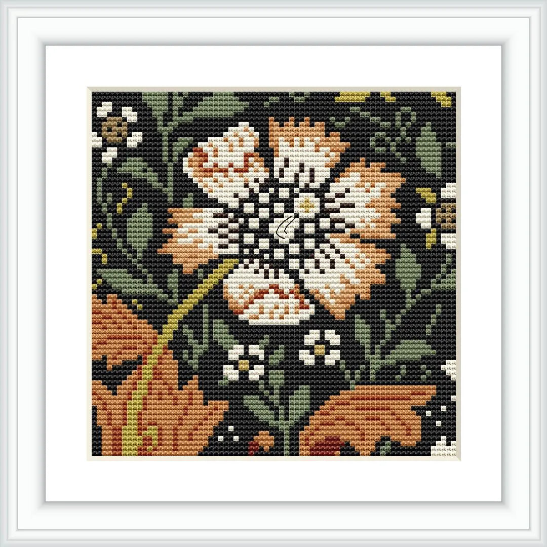 The image showcases a framed cross stitch pattern featuring a centrally located floral design with a dominant flower surrounded by leaves and other floral motifs, all against a dark background.