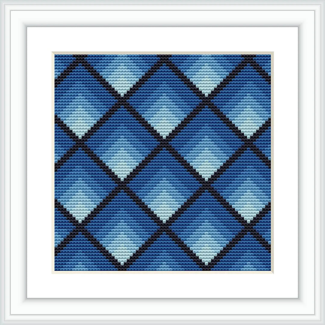 The image shows a framed cross stitch pattern featuring a geometric diamond design. The diamonds are arranged in a grid, varying in shades of blue, and are contained within a white square frame.