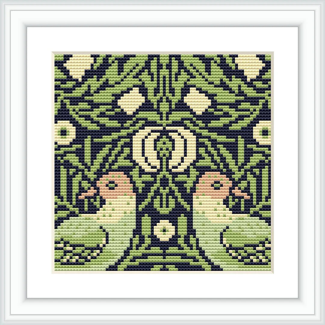 The image displays a framed cross stitch pattern resembling a mirror image with birds facing each other surrounded by an array of stylized flowers and foliage. It's a symmetrical and ornate pattern predominantly in green hues.