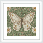 The image showcases a cross-stitch pattern with a centered, detailed butterfly motif surrounded by a field of flowers and foliage, set against a greenish background.