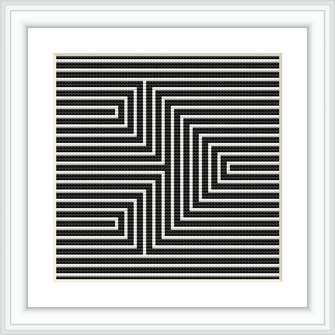 A framed cross stitch pattern with a black and white geometric arrow design creating an optical illusion, mounted on a wall or placed on a flat surface.